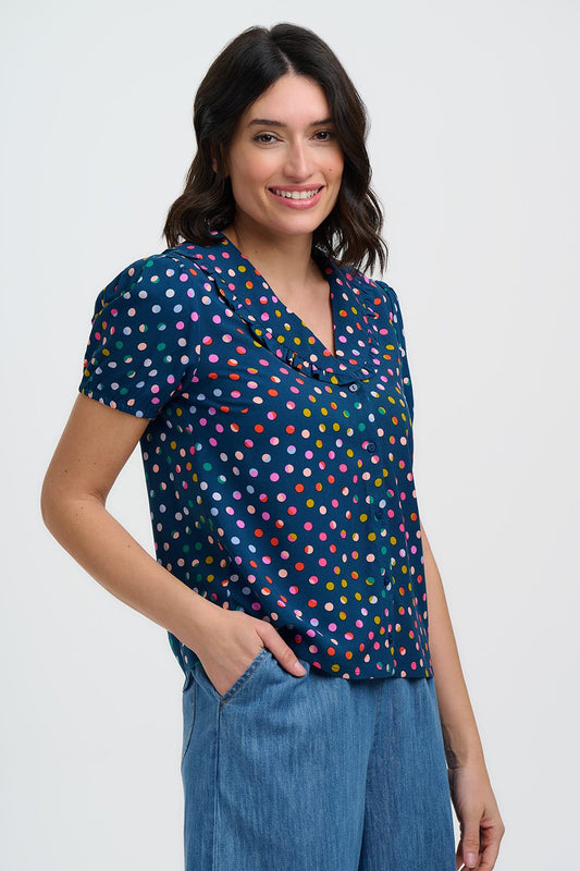 Woman wearing a colorful polka dot blouse and blue jeans on a white background