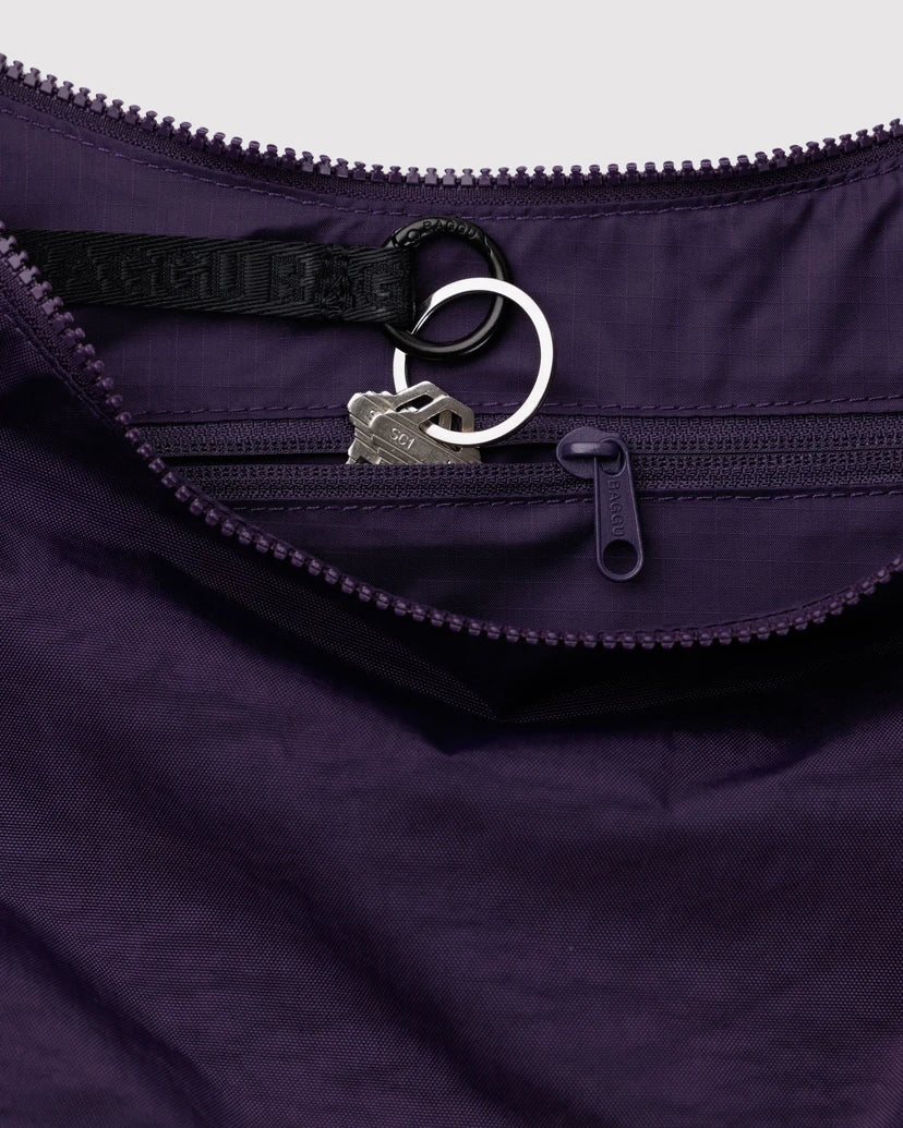 Close-up of a purple bag featuring the with inner zipper and a brand logo key chain.