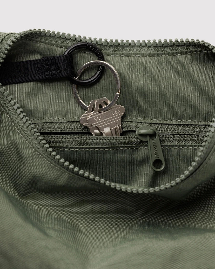 Close up of the inside of the Caper bag featuring a zipper pocket and with a keychain attached.