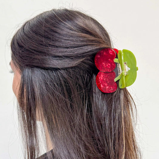 Model with a red and green cherries hair clip in their hair against a white background