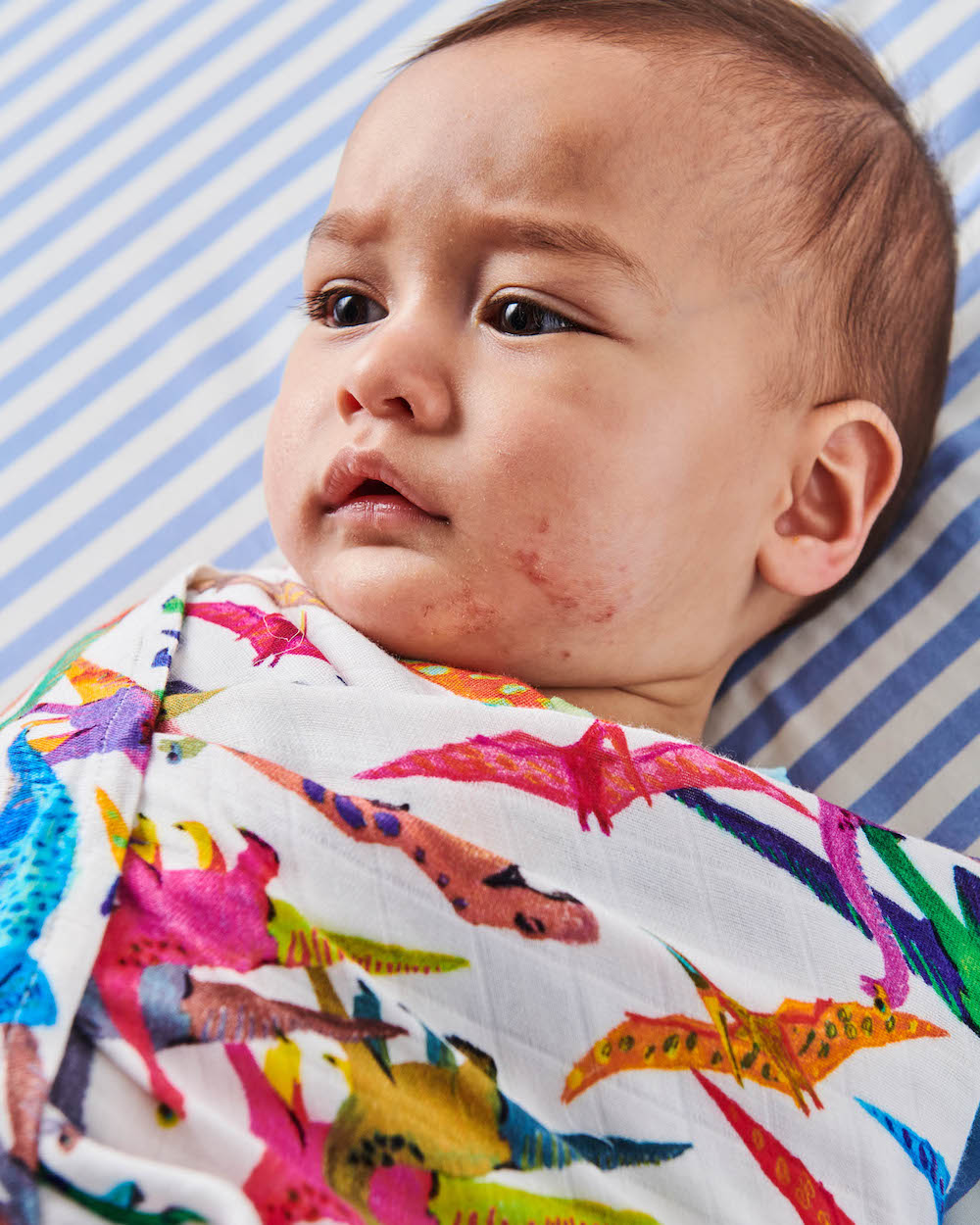 Close up of Kip & Co Dino Max Bamboo Baby Swaddle modelled by baby