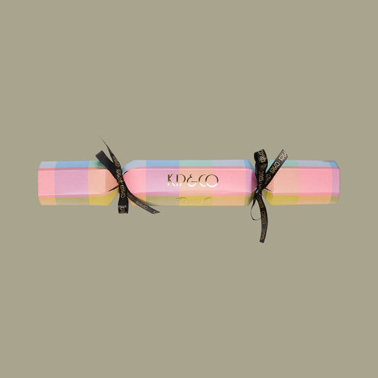 Packaging for Kip & Co Florida Tartan Velvet Eye Mask - Colorful tartan patterned cracker with black ribbons on a beige background