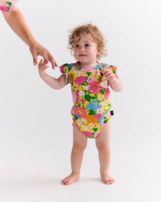 Child wearing a colorful floral romper on a white background