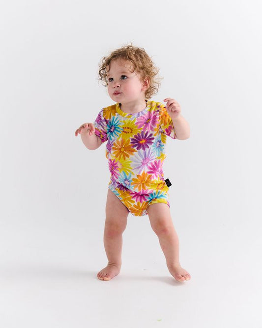Child wearing a colorful floral onesie on a white background