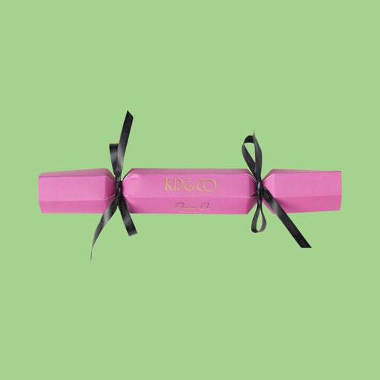 Packaging for Kip & Co Pink Velvet Eye Mask - Pink cracker with black ribbons on a green background
