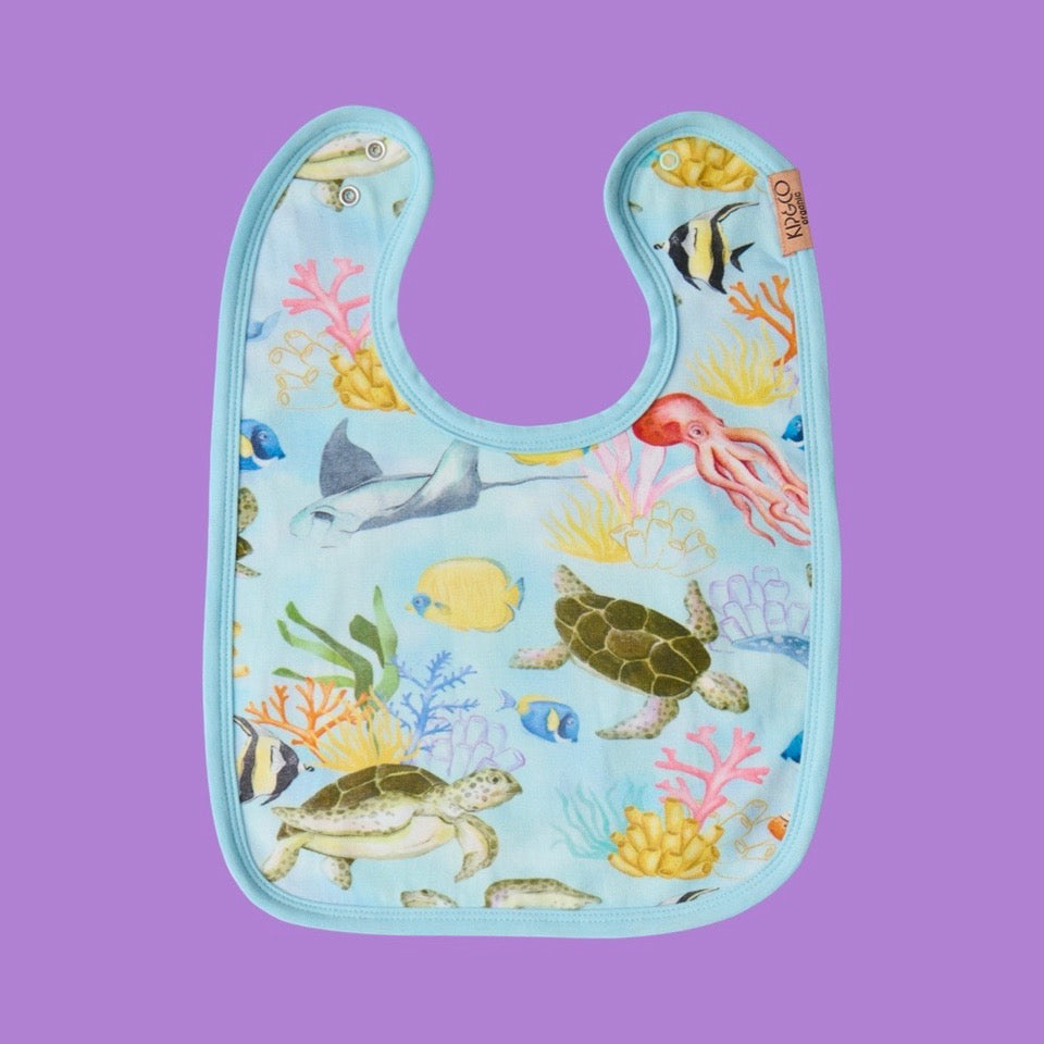 Kip & Co Reef Life Bib is a baby bib with ocean-themed design on a purple background