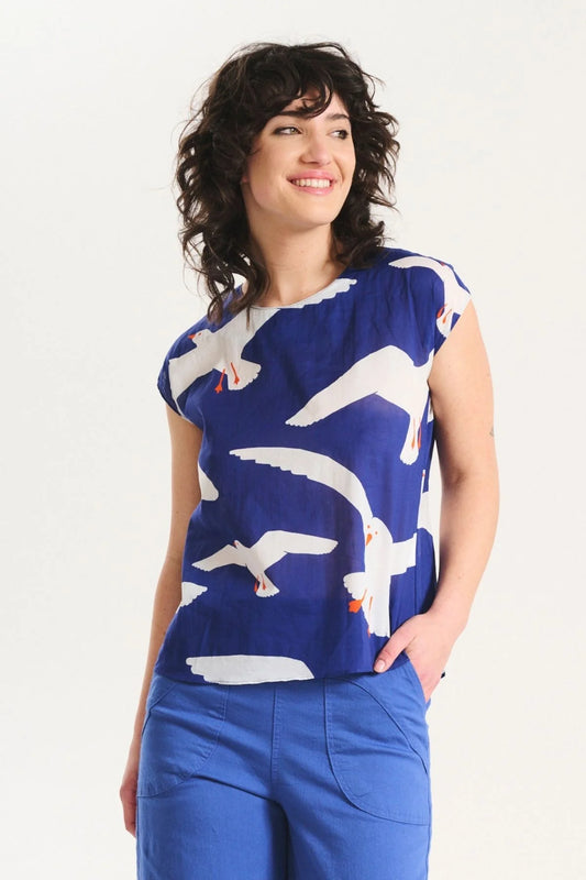 Woman wearing a blue top with white bird pattern on a white background