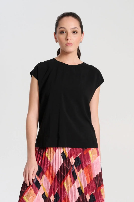 Olga de Polga Rhea Tee Black in Tencel modelled on a model who is wearing the tee and pairing it with a patterned red skirt.