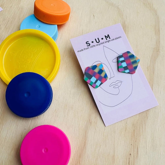 Colorful plastic lids on a wooden surface with a product packaging featuring earrings.