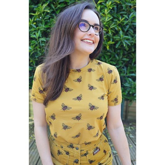 Person wearing a honey-coloured tee with bee print.