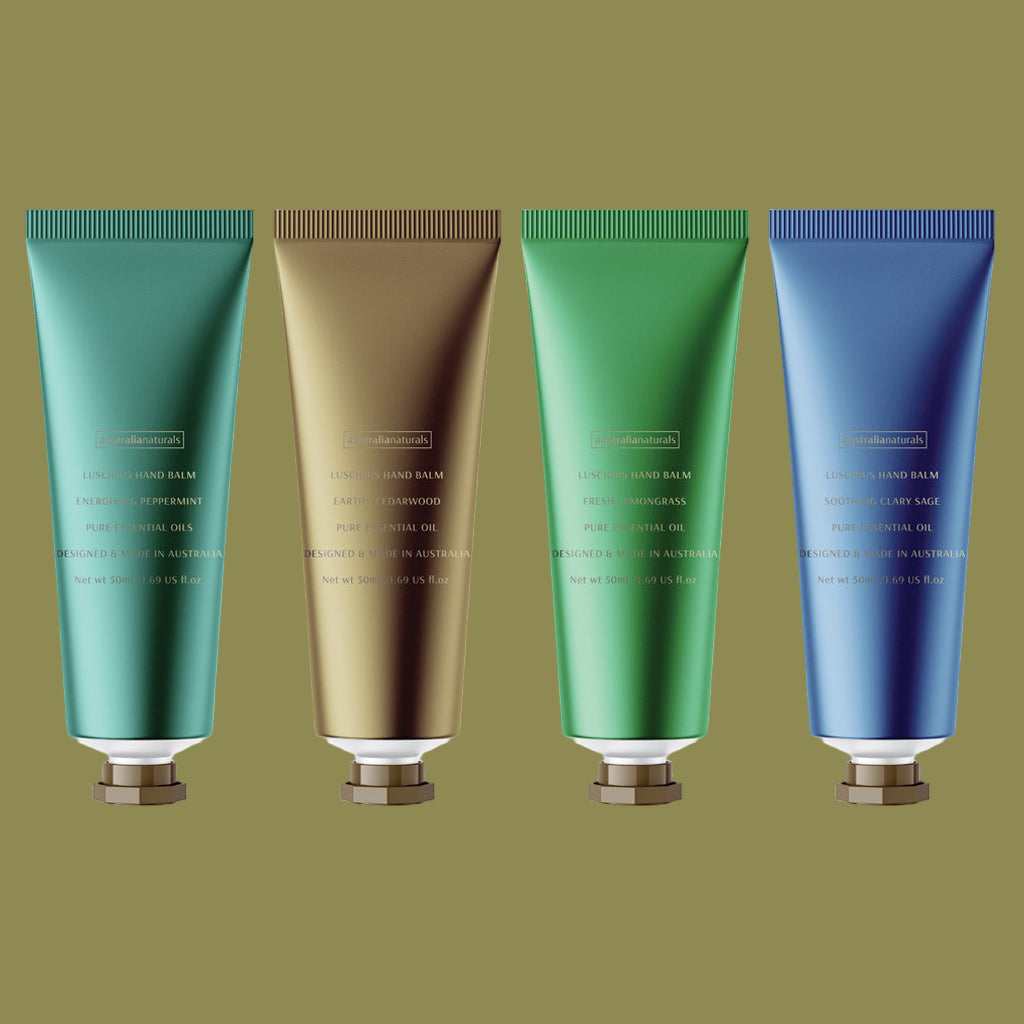 Four tubes of hand balm in teal, gold, green, and blue on a green background.