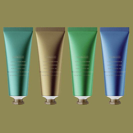Four tubes of hand balm in teal, gold, green, and blue on a green background.