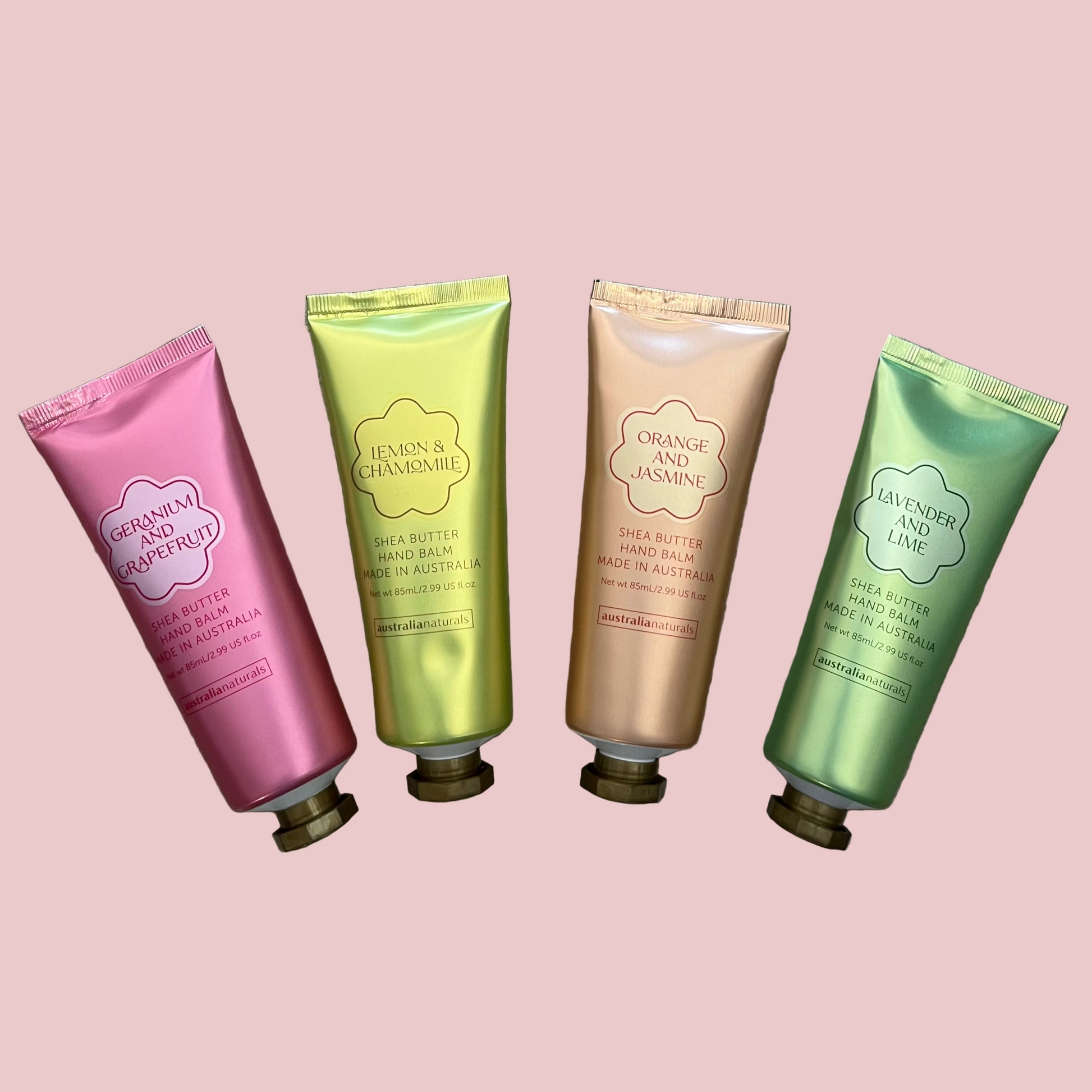 Four tube hand balms of different colors on a gray surface