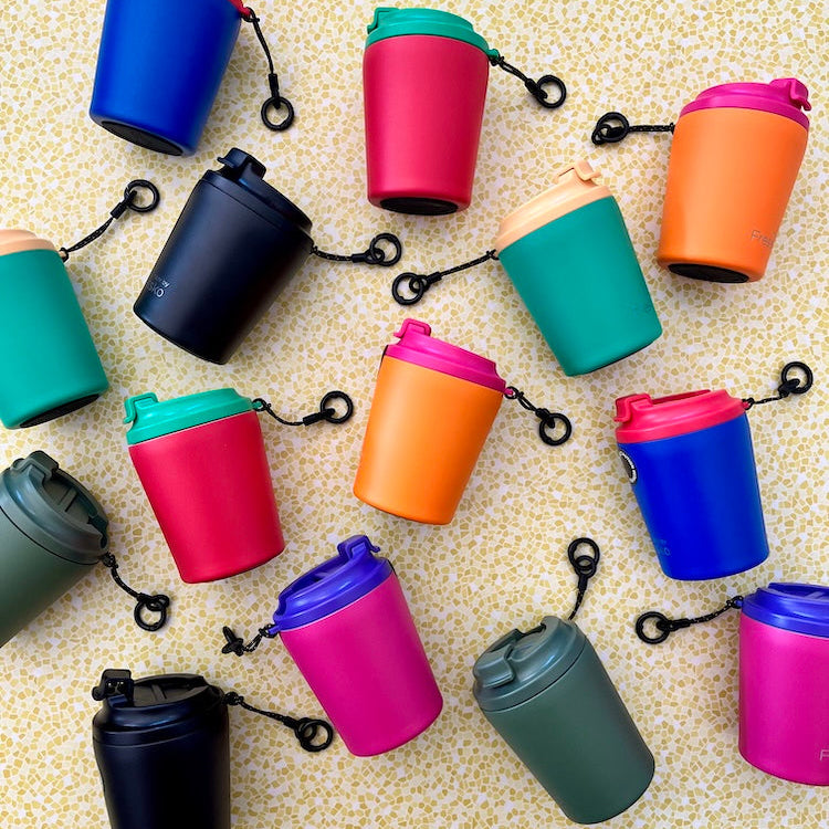 Colorful reuseable coffee cups with hang loops on a textured surface