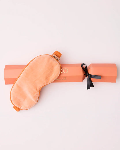 Kip&Co Melon Velvet Eye Mask is on top of its matching Christmas bon-bon-shaped gift box.