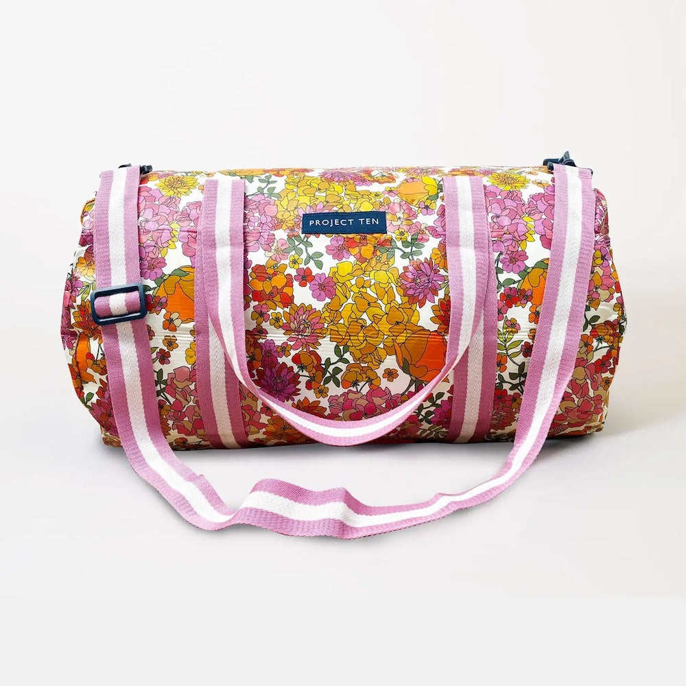 Floral patterned duffel bag with pink straps on a white background