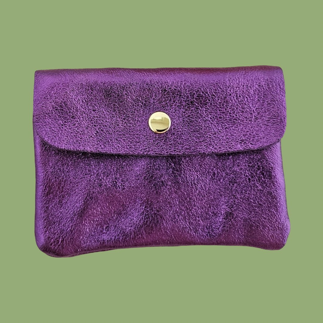 Purple metallic textured clutch with a gold button on a green background