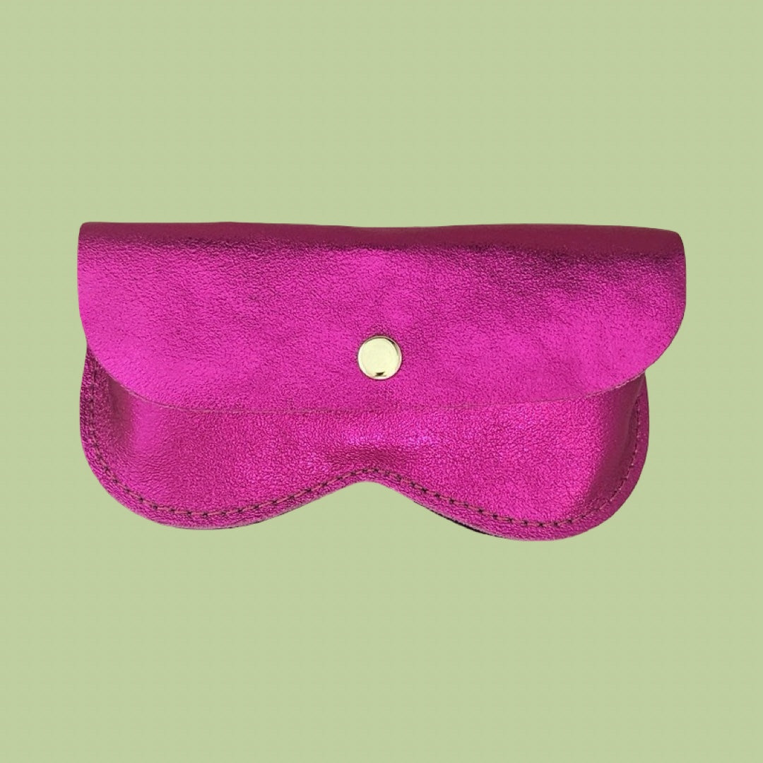 A bright magenta pink leather glasses case with a small gold snap button, shown against a solid light green background.