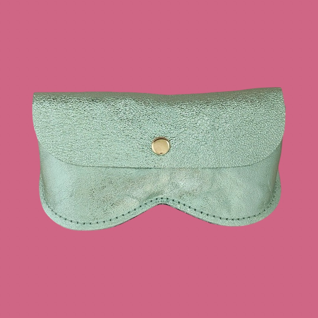 An olive green leather glasses case with a pink background