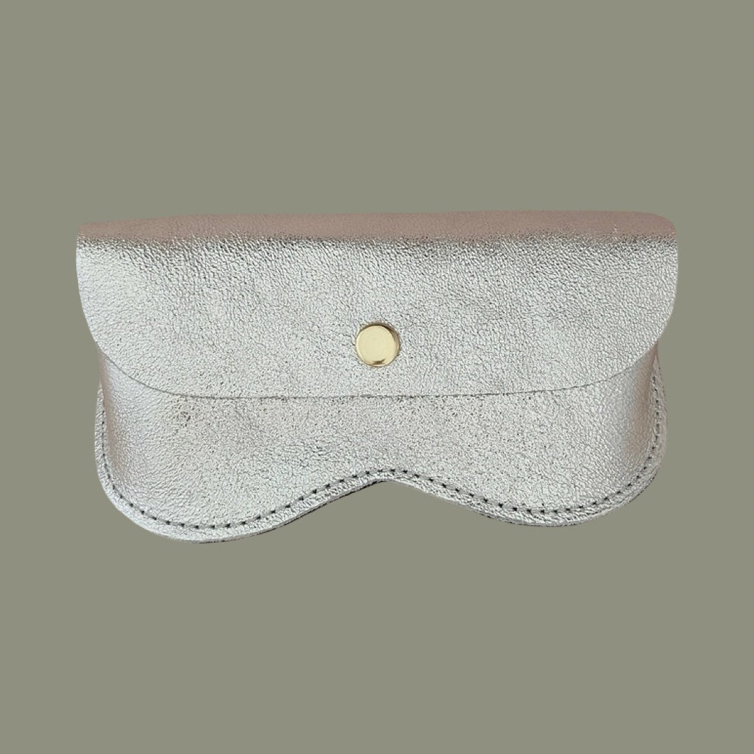 A silver textured leather glasses case with a scalloped edge and a gold snap button, shown against a solid gray background.