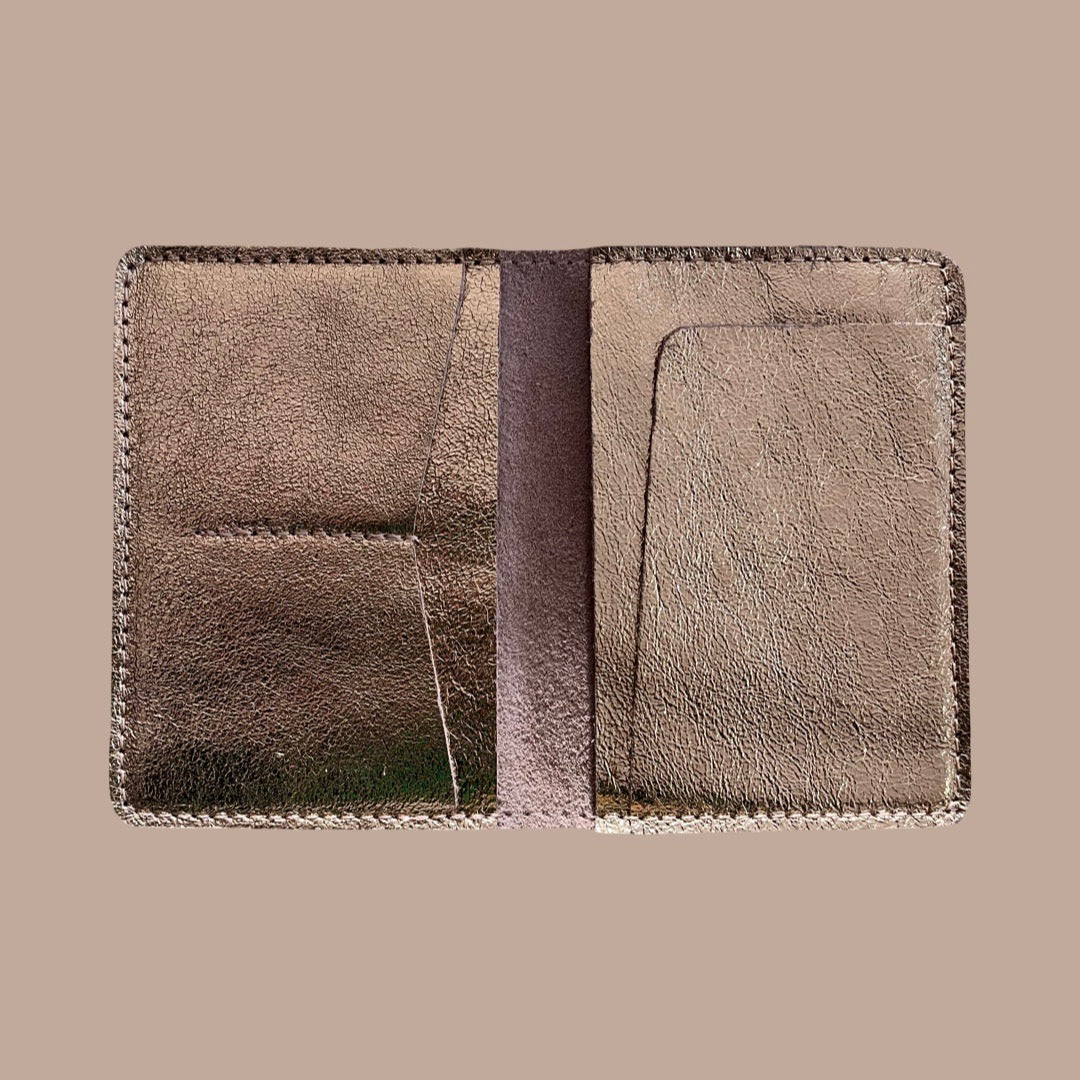 Metallic gold leather passport holder with a textured finish on a beige background