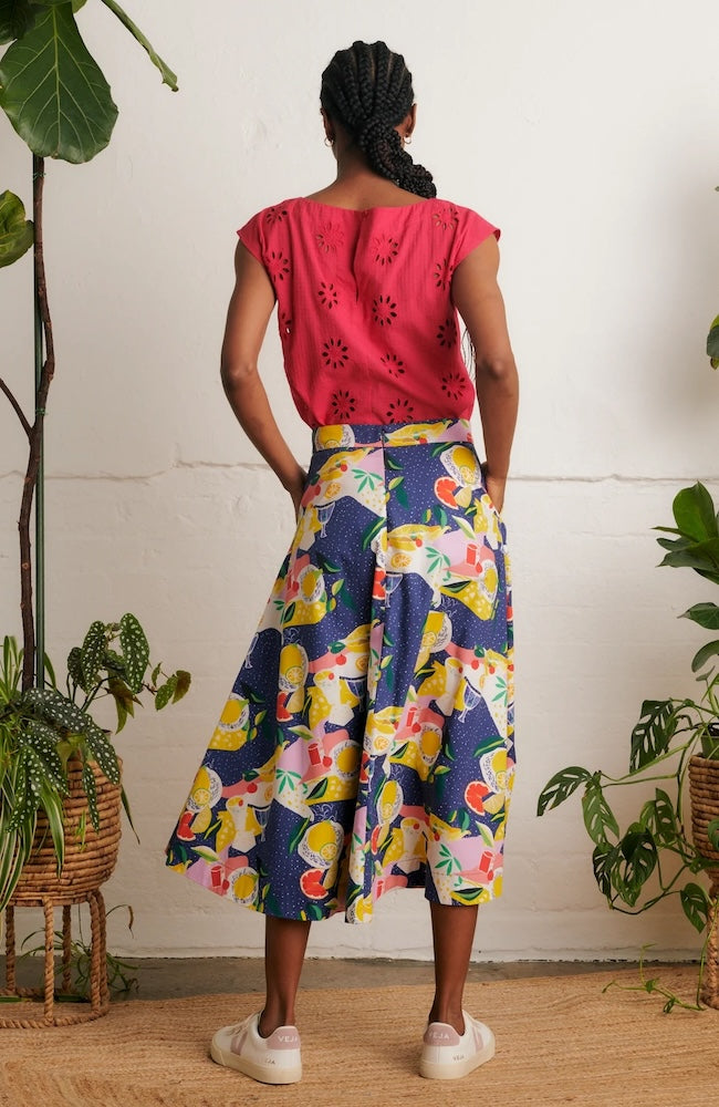 Back view of model wearing Emily & Fin Sandra Picnic Party Skirt paired with a coral coloured top and white sneakers.