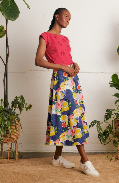 Side view of model wearing Emily & Fin Sandra Picnic Party Skirt paired with a coral coloured top and white sneakers