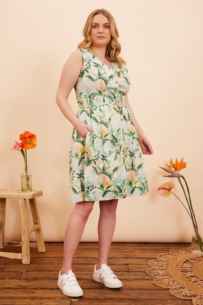 Model is wearing Emily & Fin Scarlett Victorian Glasshouse Dress paired with white sneakers. Model has a hand in a side pocket of the dress.