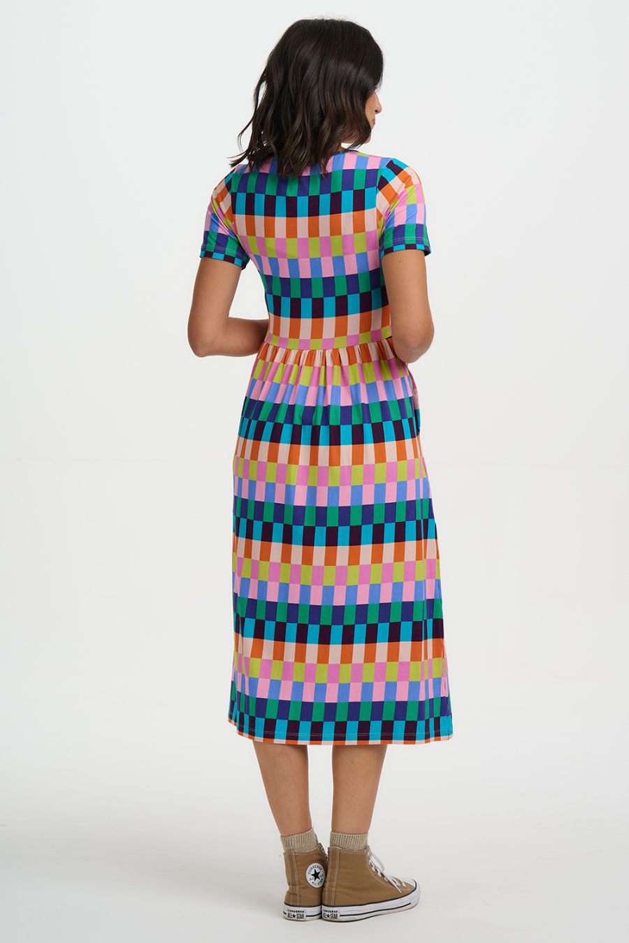 Back view of Woman wearing a colorful checkered dress on a white background