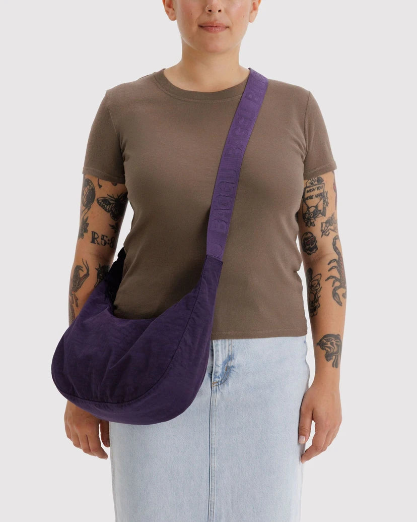 Person wearing a brown shirt and light blue jeans with a purple shoulder bag on a white background