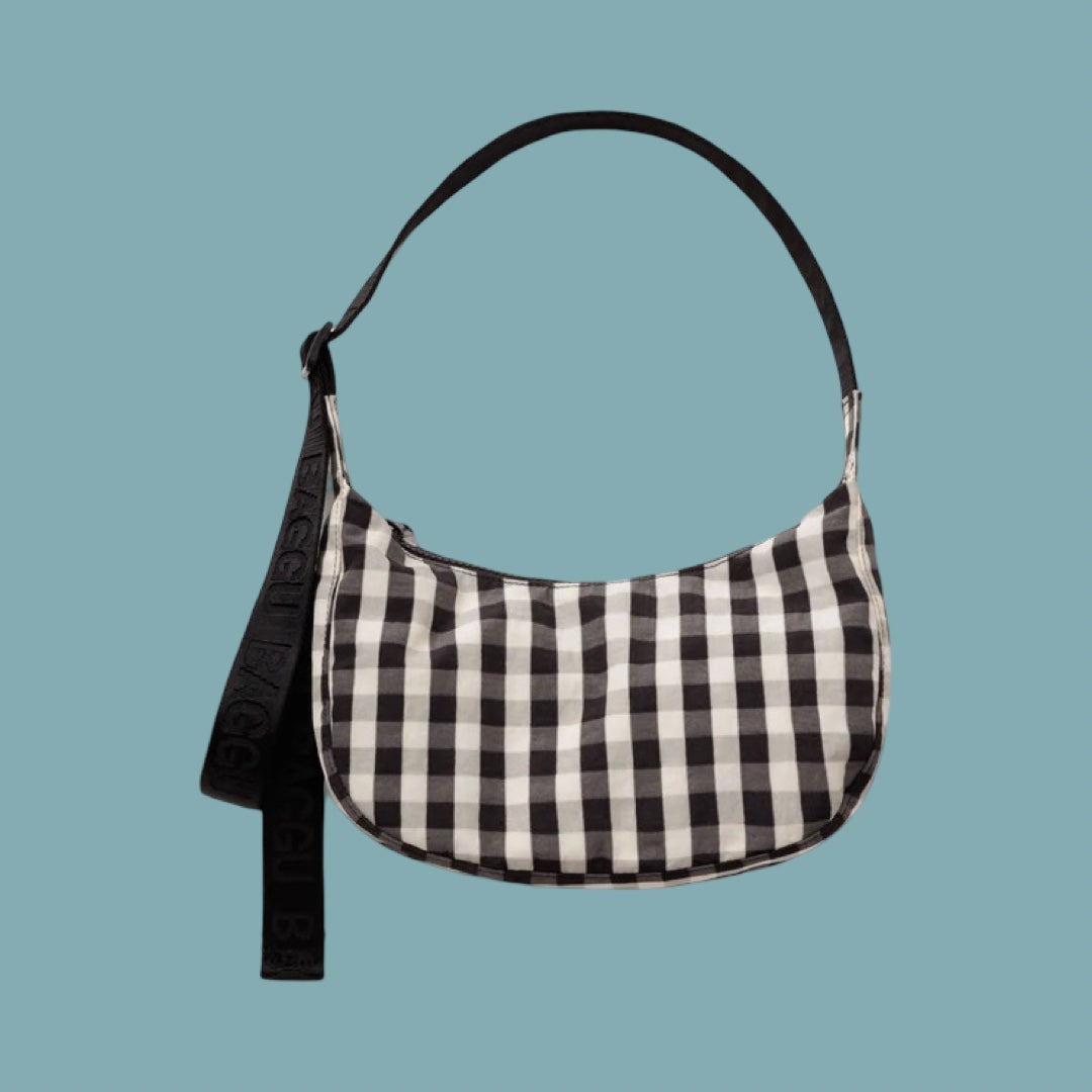 Baggu Small Crescent Bag - Gingham. A black and white gingham checkered shoulder bag with a black strap, shown against a solid light blue background.