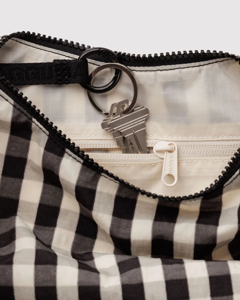 Close up of a Black and white checkered bag featuring the inside cream coloured lining with a zipper and keychain attached to it.