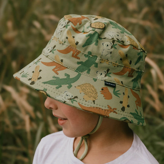 Side view of Child wearing a Australian animal-patterned hat in a grassy field