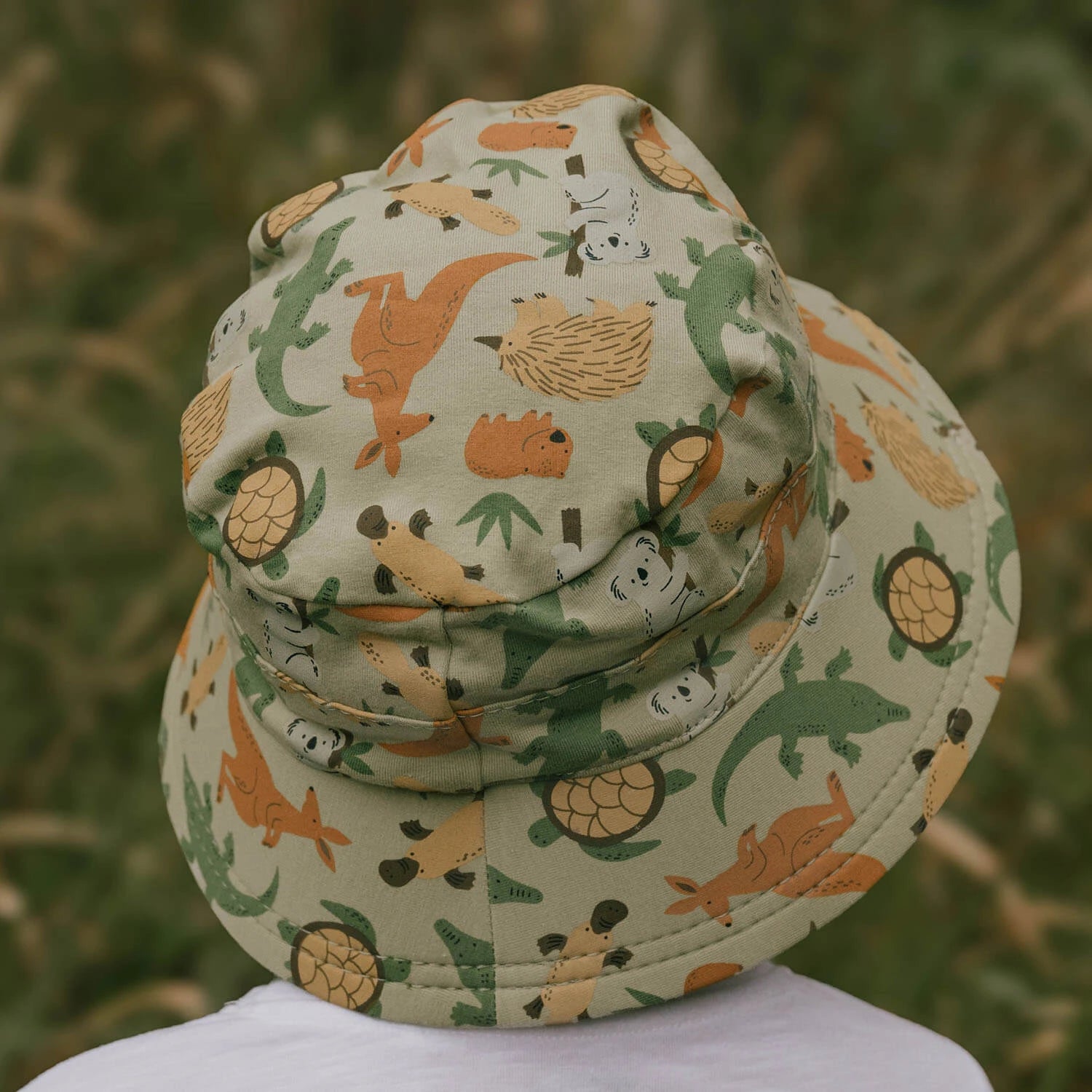 Back view of Children's bucket hat with Australian animal pattern on a blurred natural background
