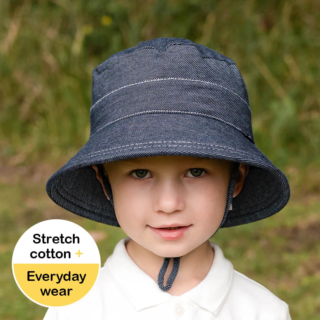 Child wearing a denim bucket hat with a grassy background