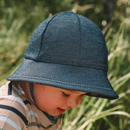 Side view of Toddler wearing a blue-black denim hat in a natural setting