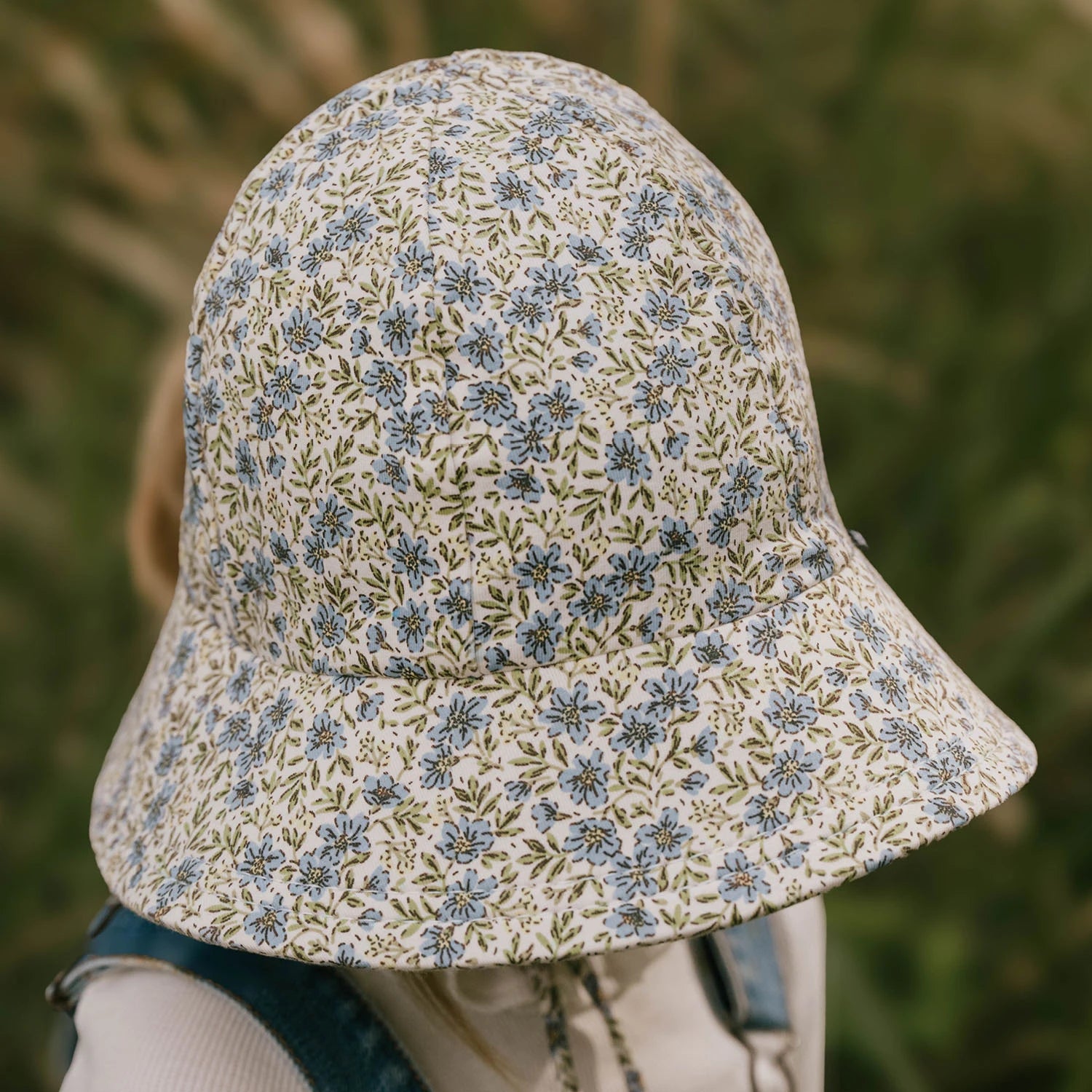 Top view of Floral patterned bucket hat worn by a child with a blurred natural background
