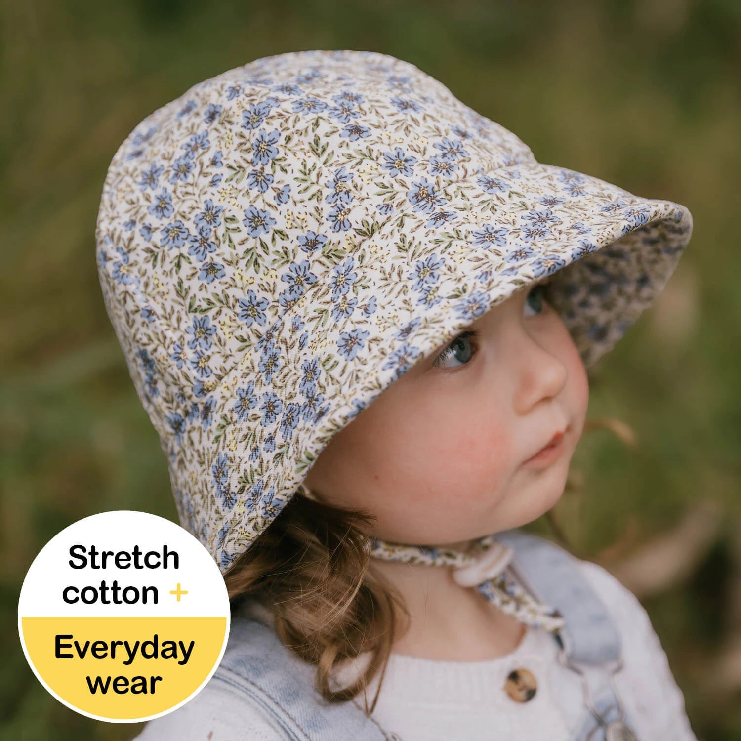 Toddler wearing a floral sun hat with a natural background