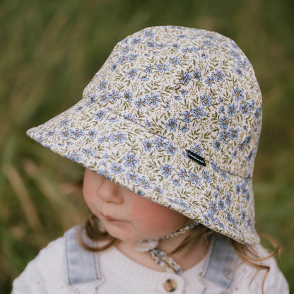 Top side view of toddler wearing a floral sun hat in a natural setting