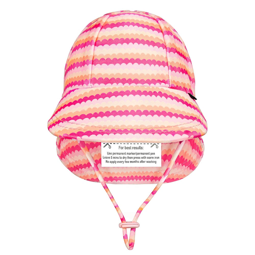 A pink and peach scalloped striped swim hat with a chin strap, shown against a plain white background.