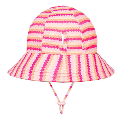 A swim bucket hat with a vibrant pink and peach scalloped stripe pattern, featuring a chin strap with a toggle.