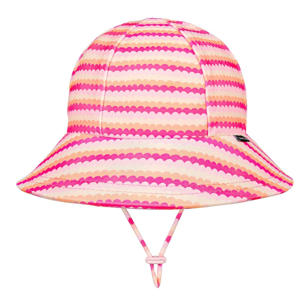 A swim bucket hat with a vibrant pink, orange and white scalloped horizontal stripe pattern, featuring a matching chin strap on a solid white background.