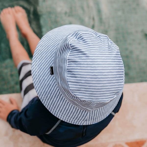 Top view of Bedhead Stevie Stripe Swim Bucket Hat worn by a young model with their feet dipping into the swimming pool