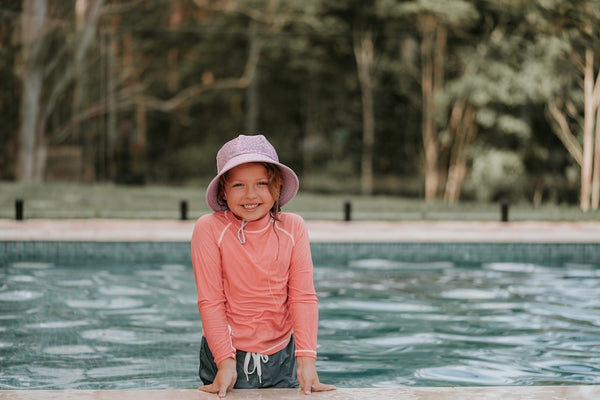 Bedhead Lila Swim Bucket Hat worn by young model on the edge of a swimming pool