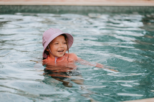 Bedhead Lila Swim Bucket Hat worn by a young model in a swimming pool