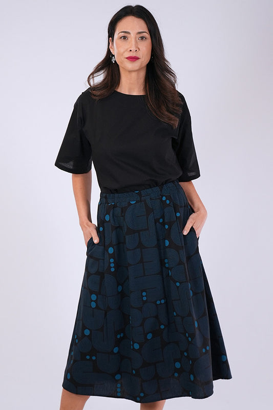 Model wears Essaye Isabel Bauhaus Skirt in Black/Blue with hands in side pockets.