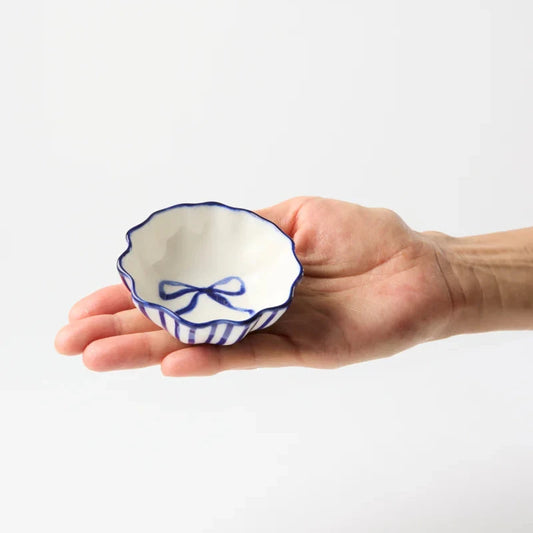 Hand holding a small ceramic bowl with blue decorative elements on a white background