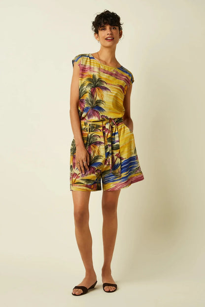 Woman wearing a colourful, vintage-inspired tropical print top and shorts on a plain beige background