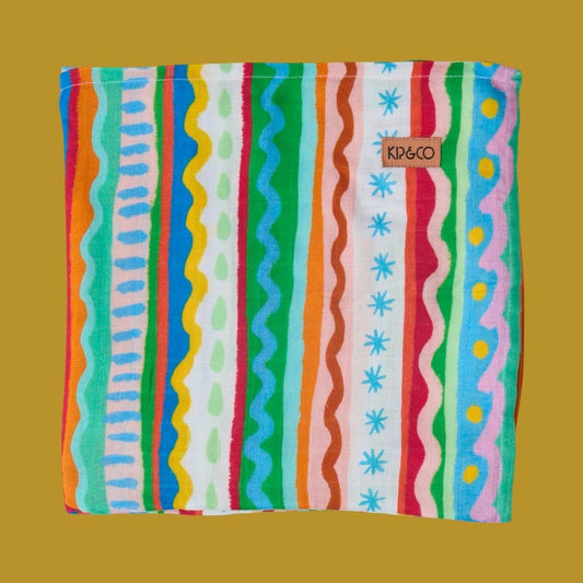 Kip & Co Beach Patterns Bamboo Baby Swaddle is a colorful striped cloth with 'Kip & Co' branding on a yellow background