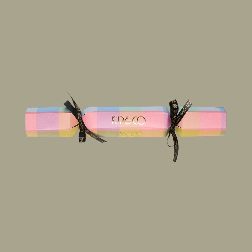 Packaging for Kip & Co Florida Tartan Velvet Eye Mask - Colorful tartan patterned cracker with black ribbons on a beige background